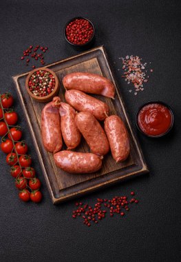 Koyu beton arka planda fırında tavuk ya da domuz sosisi, tuz, baharat ve otlar.