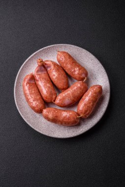 Koyu beton arka planda fırında tavuk ya da domuz sosisi, tuz, baharat ve otlar.