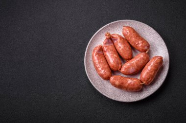 Koyu beton arka planda fırında tavuk ya da domuz sosisi, tuz, baharat ve otlar.