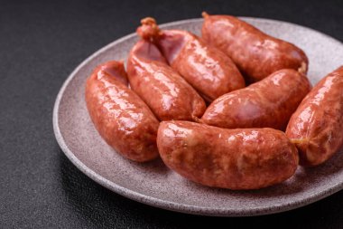 Koyu beton arka planda fırında tavuk ya da domuz sosisi, tuz, baharat ve otlar.