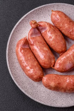 Koyu beton arka planda fırında tavuk ya da domuz sosisi, tuz, baharat ve otlar.