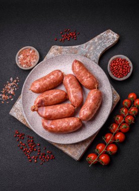 Koyu beton arka planda fırında tavuk ya da domuz sosisi, tuz, baharat ve otlar.