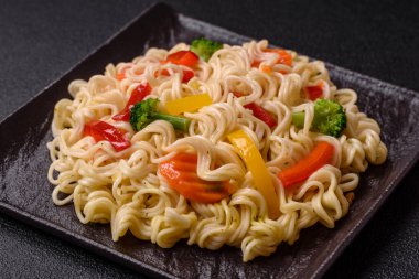 Lezzetli Asya yemeği pirinç eriştesi ya da koyu beton arka planda sebzeli, baharatlı ve otlu udon.