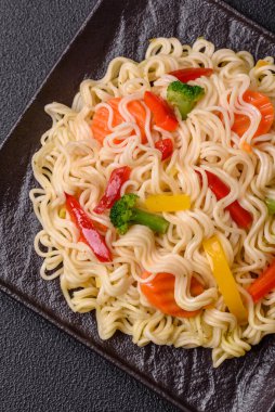 Lezzetli Asya yemeği pirinç eriştesi ya da koyu beton arka planda sebzeli, baharatlı ve otlu udon.