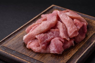 Koyu beton arka planda tuzlu, baharatlı ve otlu çiğ domuz eti veya hindi eti dilimleri