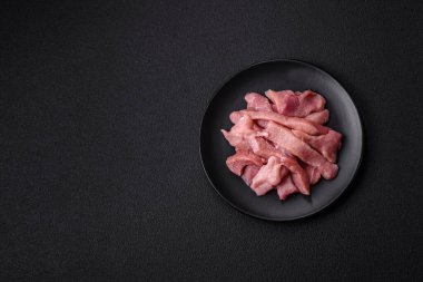 Koyu beton arka planda tuzlu, baharatlı ve otlu çiğ domuz eti veya hindi eti dilimleri