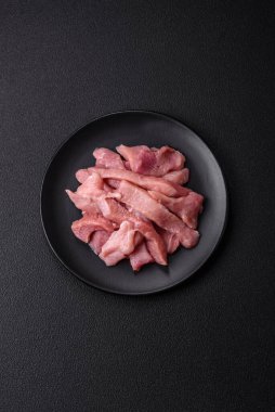 Koyu beton arka planda tuzlu, baharatlı ve otlu çiğ domuz eti veya hindi eti dilimleri
