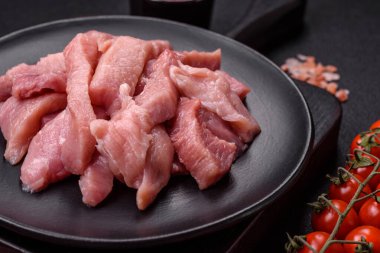 Koyu beton arka planda tuzlu, baharatlı ve otlu çiğ domuz eti veya hindi eti dilimleri