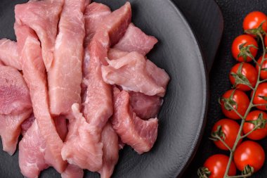 Koyu beton arka planda tuzlu, baharatlı ve otlu çiğ domuz eti veya hindi eti dilimleri