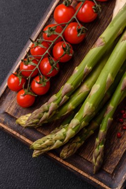 Koyu beton zeminde sağlıklı bir kahvaltı hazırlamak için malzeme olarak çiğ yeşil kuşkonmaz.