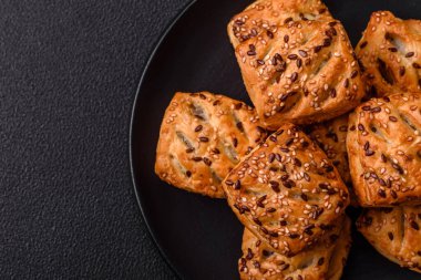 Feta peynirli üçgen puflar, esmer arka planda tuzlu domatesler, baharatlar ve otlar.