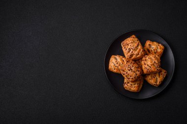 Feta peynirli üçgen puflar, esmer arka planda tuzlu domatesler, baharatlar ve otlar.