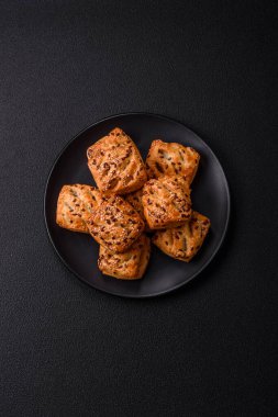 Feta peynirli üçgen puflar, esmer arka planda tuzlu domatesler, baharatlar ve otlar.