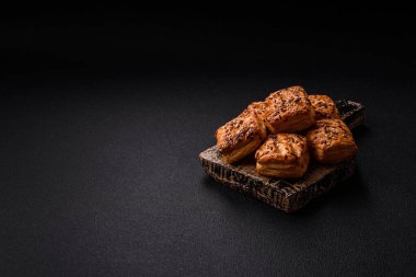 Feta peynirli üçgen puflar, esmer arka planda tuzlu domatesler, baharatlar ve otlar.