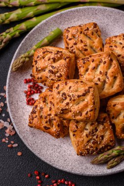 Feta peynirli üçgen puflar, esmer arka planda tuzlu domatesler, baharatlar ve otlar.