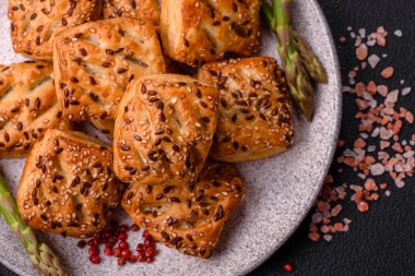 Feta peynirli üçgen puflar, esmer arka planda tuzlu domatesler, baharatlar ve otlar.