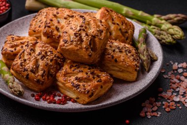 Feta peynirli üçgen puflar, esmer arka planda tuzlu domatesler, baharatlar ve otlar.