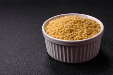 Koyu beton zemin üzerinde tuz ve baharatlı buğdaydan ham stelline makarna