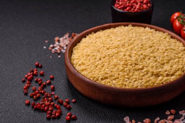 Koyu beton zemin üzerinde tuz ve baharatlı buğdaydan ham stelline makarna