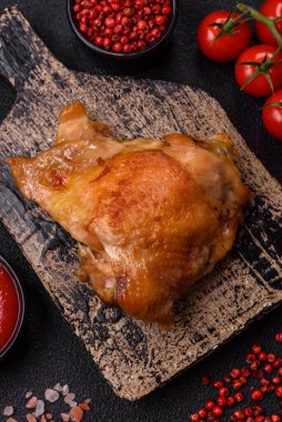 Izgarada pişirilmiş lezzetli sulu tavuk butları. Koyu beton bir arka planda tuz, baharat ve otlarla.