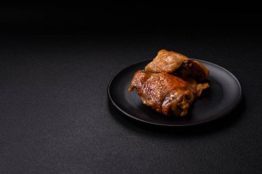 Izgarada pişirilmiş lezzetli sulu tavuk butları. Koyu beton bir arka planda tuz, baharat ve otlarla.