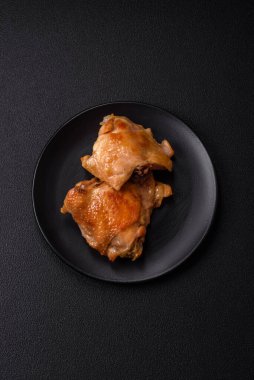 Izgarada pişirilmiş lezzetli sulu tavuk butları. Koyu beton bir arka planda tuz, baharat ve otlarla.