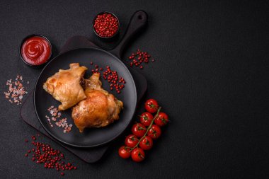 Izgarada pişirilmiş lezzetli sulu tavuk butları. Koyu beton bir arka planda tuz, baharat ve otlarla.