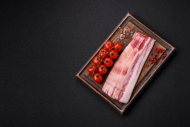 Tuz, baharat ve otlarla dilimlenmiş lezzetli pastırma koyu beton arka planda.