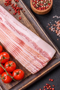 Tuz, baharat ve otlarla dilimlenmiş lezzetli pastırma koyu beton arka planda.