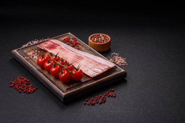 Tuz, baharat ve otlarla dilimlenmiş lezzetli pastırma koyu beton arka planda.