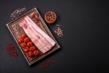 Tuz, baharat ve otlarla dilimlenmiş lezzetli pastırma koyu beton arka planda.