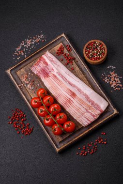 Tuz, baharat ve otlarla dilimlenmiş lezzetli pastırma koyu beton arka planda.