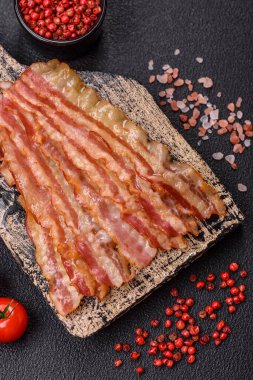 Tuz, baharat ve otlarla dilimlenmiş lezzetli pastırma koyu beton arka planda.