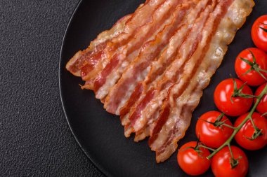 Tuz, baharat ve otlarla dilimlenmiş lezzetli pastırma koyu beton arka planda.