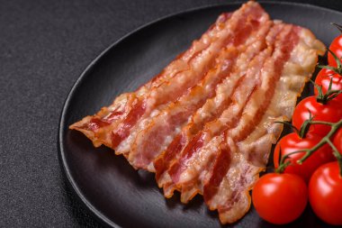 Tuz, baharat ve otlarla dilimlenmiş lezzetli pastırma koyu beton arka planda.