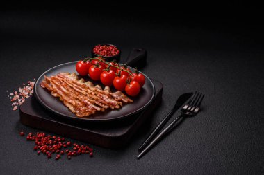 Tuz, baharat ve otlarla dilimlenmiş lezzetli pastırma koyu beton arka planda.