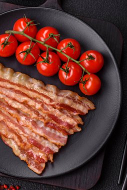 Tuz, baharat ve otlarla dilimlenmiş lezzetli pastırma koyu beton arka planda.