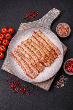 Tuz, baharat ve otlarla dilimlenmiş lezzetli pastırma koyu beton arka planda.