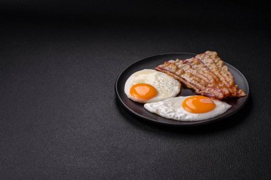 Yağda yumurta, pastırma, fasulye, domates, baharat ve bitkilerle İngiliz kahvaltısı. Güne doyurucu ve doyurucu bir başlangıç.