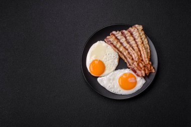 Yağda yumurta, pastırma, fasulye, domates, baharat ve bitkilerle İngiliz kahvaltısı. Güne doyurucu ve doyurucu bir başlangıç.