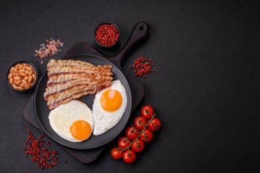 Yağda yumurta, pastırma, fasulye, domates, baharat ve bitkilerle İngiliz kahvaltısı. Güne doyurucu ve doyurucu bir başlangıç.