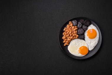 Yağda yumurta, pastırma, fasulye, domates, baharat ve bitkilerle İngiliz kahvaltısı. Güne doyurucu ve doyurucu bir başlangıç.