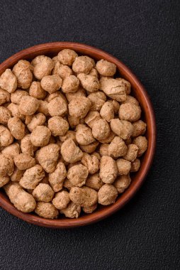 Kuru soya fasulyesi topakları, vejetaryen ve vejetaryen mutfağı için diyet yiyecekler koyu beton arka planda.