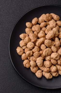 Kuru soya fasulyesi topakları, vejetaryen ve vejetaryen mutfağı için diyet yiyecekler koyu beton arka planda.