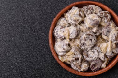 Kaynamış tavuk kalbi soğan ve krema sosuyla dilimlenmiş koyu beton arka planda tuz ve baharatla kesilmiş.