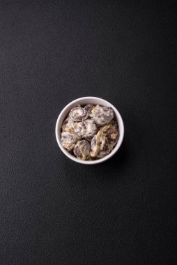 Kaynamış tavuk kalbi soğan ve krema sosuyla dilimlenmiş koyu beton arka planda tuz ve baharatla kesilmiş.