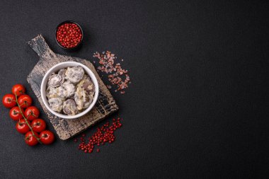 Kaynamış tavuk kalbi soğan ve krema sosuyla dilimlenmiş koyu beton arka planda tuz ve baharatla kesilmiş.