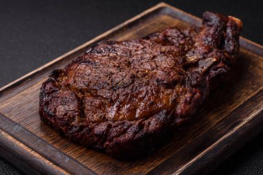 Tuz, baharat ve otlarla ızgarada kızartılmış lezzetli biftekli biftek ve çimento arka planda.