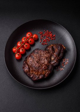 Tuz, baharat ve otlarla ızgarada kızartılmış lezzetli biftekli biftek ve çimento arka planda.