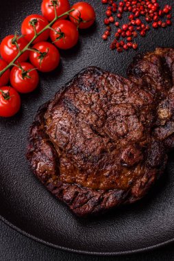 Tuz, baharat ve otlarla ızgarada kızartılmış lezzetli biftekli biftek ve çimento arka planda.